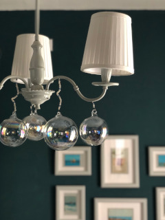 Il vecchio lampadario reinterpretato con le sfere in vetro soffiato simili a bolle di sapone e i paralumi i plissettati a nascondere le lampadine